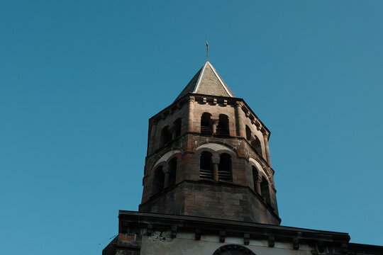 Clocher octogonal en pierre volcanique sous un ciel bleu, architecture romane d'Auvergne, Rochefort-Montagne