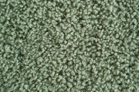 Sage green boucle or faux fur textile texture. Soft curly fiber pattern ideal for interior design, cozy winter upholstery or fashion fabric backgrounds