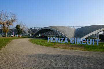 Obraz premium Iconic Monza Circuit entrance with modern curved architecture and bold signage, captured on a sunny day in Italy, symbolizing speed, motorsport heritage, and innovation.