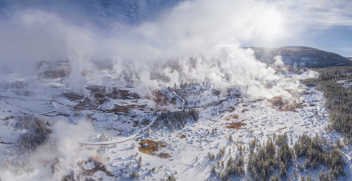 Aerial view of steam rising from the geysers contrasting with the snow-covered landscape, Yellowstone National Park, Wyoming, United States.