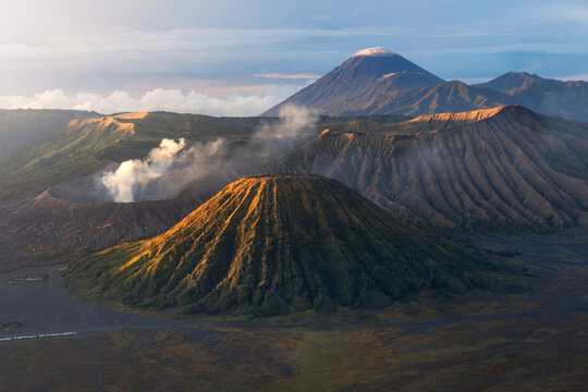 Aerial view of majestic Mount Bromo shrouded in ethereal mists, its volcanic peak contrasting with the rugged terrain, East Java, Indonesia.
