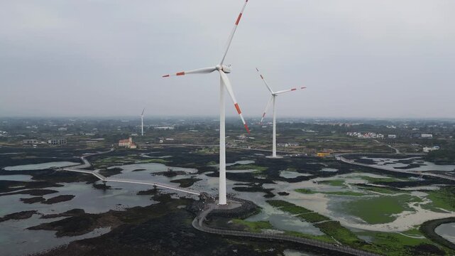Jeju Island, Jeju-Do, South Korea,  Sinchang Windmill Coastal Road landscape, line of wind mills power generators along the coast, offshore wind farm energy turbines, aerial drone view, green energy
