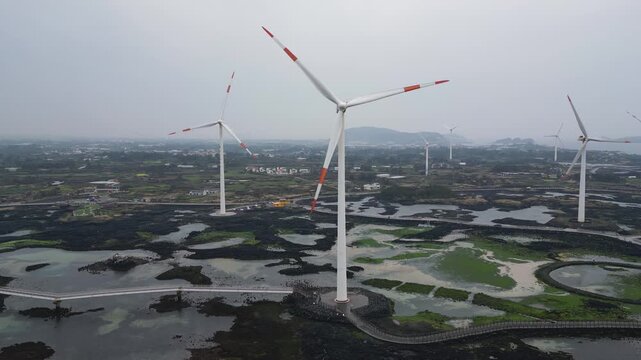 Jeju Island, Jeju-Do, South Korea,  Sinchang Windmill Coastal Road landscape, line of wind mills power generators along the coast, offshore wind farm energy turbines, aerial drone view, green energy