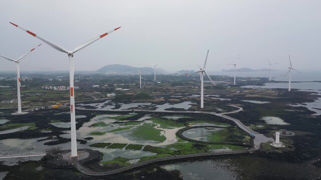 Jeju Island, Jeju-Do, South Korea,  Sinchang Windmill Coastal Road landscape, line of wind mills power generators along the coast, offshore wind farm energy turbines, aerial drone view, green energy