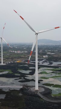 Jeju Island, Jeju-Do, South Korea,  Sinchang Windmill Coastal Road landscape, line of wind mills power generators along the coast, offshore wind farm energy turbines, aerial drone view, green energy
