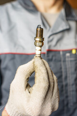 A mechanic holds old spark plugs. Defective spark plugs, stained with motor oil. Soot on the spark plugs.