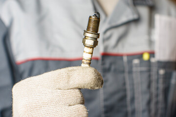 A mechanic holds old spark plugs. Defective spark plugs, stained with motor oil. Soot on the spark plugs.
