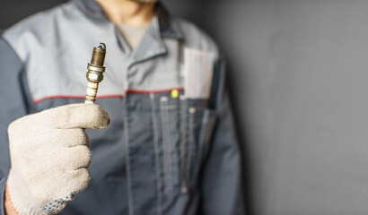 A mechanic holds old spark plugs. Defective spark plugs, stained with motor oil. Soot on the spark plugs.