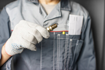A mechanic holds old spark plugs. Defective spark plugs, stained with motor oil. Soot on the spark plugs.