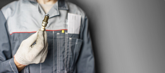 A mechanic holds old spark plugs. Defective spark plugs, stained with motor oil. Soot on the spark plugs.