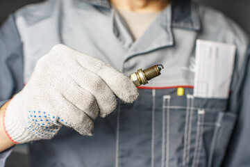 A mechanic holds old spark plugs. Defective spark plugs, stained with motor oil. Soot on the spark plugs.