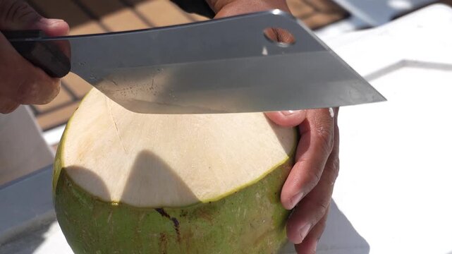 Opening a coconut. Opening a coconut with a large cleaver on a yacht, close-up shot