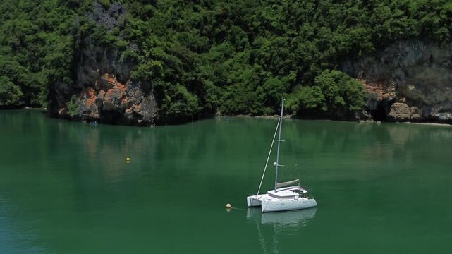 Sailing trips. Sailing yacht off Panak Island, yacht trip in Thailand. Drone view of a sailing catamaran off the coast of a limestone island.