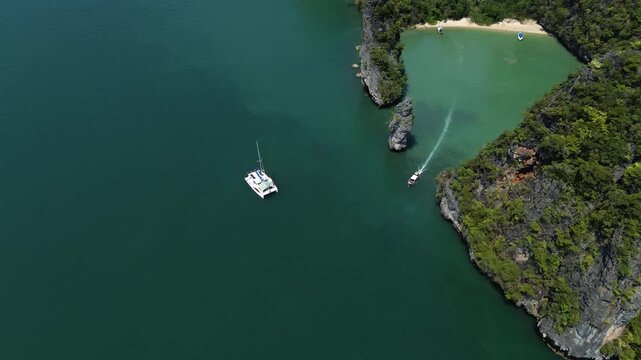 Sailing trips. Sailing yacht off Panak Island, yacht trip in Thailand. Drone view of a sailing catamaran off the coast of a limestone island.
