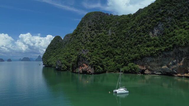 Sailing trips. Sailing yacht off Panak Island, yacht trip in Thailand. Drone view of a sailing catamaran off the coast of a limestone island.