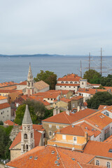 Obraz premium Aerial view Zadar, Croatia, featuring dense cluster of Mediterranean buildings with orange-tiled roofs prominent church towers rising above town.