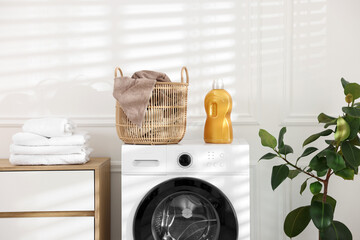 Laundry basket with dirty towel and detergent on washing machine at home