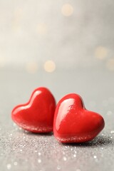 Fototapeta premium Love. Red decorative hearts on shiny gray surface against blurred background, closeup. Space for text