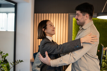 Fototapeta premium Colleagues welcoming new team member with hug in modern office