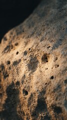 A raw stone surface illuminated by soft golden-hour light, with light reflecting off the stone texture, visual focus on natural imperfections.