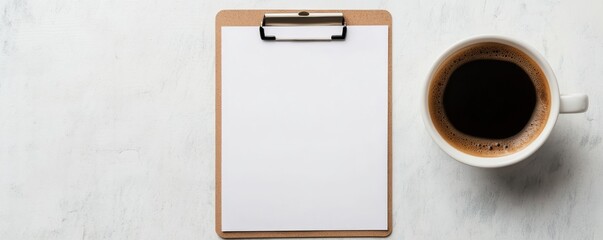 Top-down view of a clipboard with blank paper and a cup of black coffee on a textured white surface. Work, coffee break