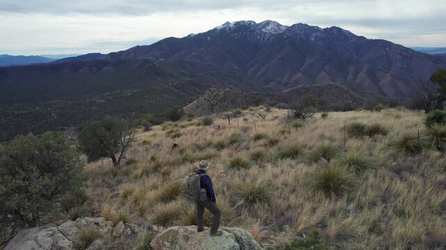 Aerial pullback of a man on a mountain summit enjoying the view