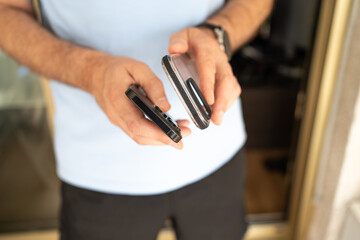 Close-up of a man holding a smartphone and a transparent protective case, preparing to put the case on the phone.