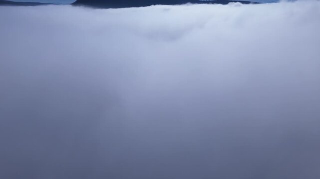 A drone climbs through thick fog and reveals a sunny day.