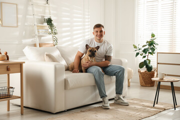 Obraz premium Young man with his cute dog relaxing on sofa at home