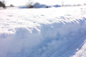 Obraz premium Tire tracks on sunlit snow, closeup. Winter season