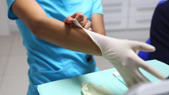 Dental assistant putting on sterile latex gloves for examination