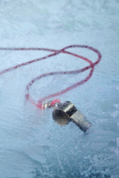 Whistle on lanyard under frozen sheet of ICE.  Social Editorial Commentary Silence 