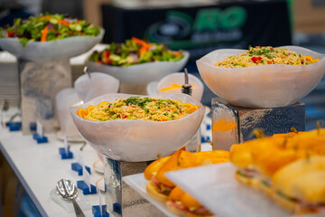 Various dishes served on plates at a buffet table, offering a wide selection of food for guests. Catering setup with assorted meals prepared for self-service dining at an event or restaurant