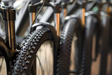 Close-up view of a row of new mountain bikes in a bicycle shop, focusing on tires and suspension.  © Jan Dzacovsky