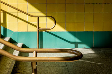 Minimalist Berlin U-Bahn Station Architecture with Yellow and Teal Tiles Brass Handrail and Dramatic Light Shadows Urban Geometric Transit Design