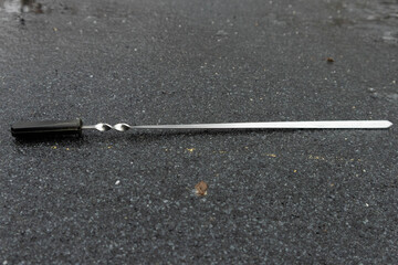 Metal tool lies on wet ground near sports field during early morning hours in quiet neighborhood setting