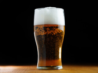 Close-up of a light foamy beer glass with bubbles on a black background