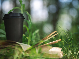 cup of coffee and an open book on the grass in the park