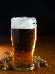 Cold beer glass in drops of water on a wooden table with a black background