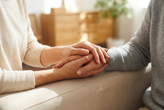 Close-up of couple holding hands during emotional conversation at home