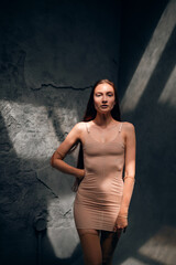 Fototapeta premium Woman stands in a bare room with one arm raised while light streams through ceiling windows during day time