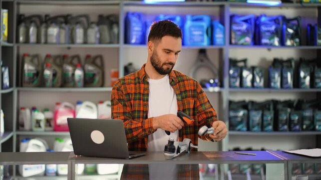 Auto parts store clerk managing inventory with laptop
