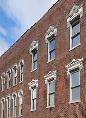 Naklejka premium The facade of an old brick building featuring beautifully designed windows. There is copy space in the image.