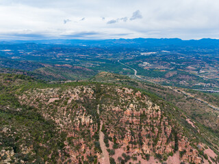 View from a high point shows mountains, valleys, and roads in a landscape during a cloudy day