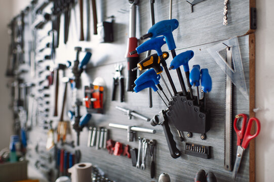 Professional bicycle workshop tool wall featuring organized blue T-handle hex keys, wrenches, and bike maintenance equipment ready for service.