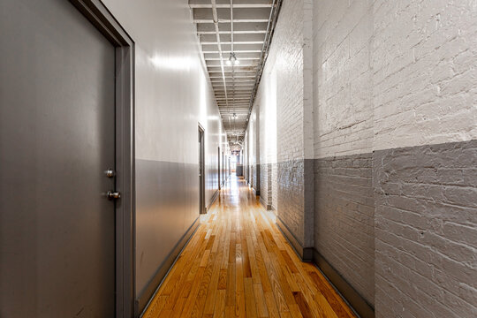 Minimal industrial apartment hallway with exposed brick walls and hardwood floor