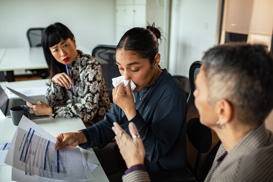Sick employee with tissue during office meeting