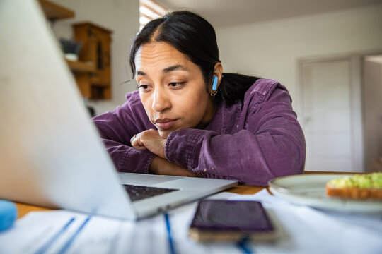 Tired woman staring at laptop while working from home in kitchen
