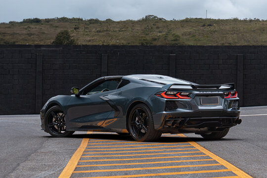 Grey Chevrolet Corvette C8 parked on yellow marked asphalt, Luxury sports car full body with cloudy sky background