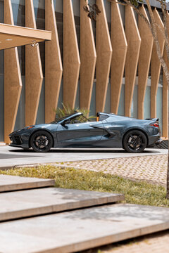 Grey Chevrolet Corvette C8 side view profile, Luxury sportscar parked at upscale residential entrance